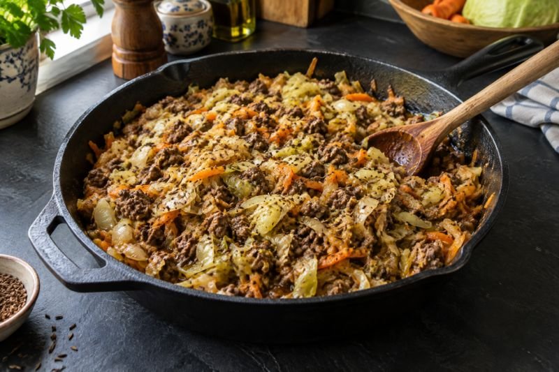 A cast-iron skillet of browned ground beef and shredded cabbage flecked with carrot and caraway